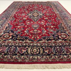 Raudonos ir mėlynos spalvų, persiškas vilnos rankų darbo kilimas su augaliniais ornamentais.