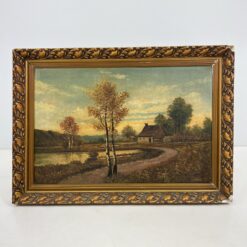 Ant drobės aliejiniais dažais tapytas paveikslas, aukso spalvos medžio ir gipso rėmu, vaizduojantis namą tvenkinio fone.