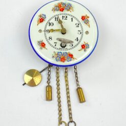 Mechaninis žalvario ir emaliuoto metalo miniatiūrinis sieninis laikrodis 4,5×6,5×12 cm