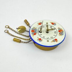 Mechaninis žalvario ir emaliuoto metalo miniatiūrinis sieninis laikrodis 4,5×6,5×12 cm