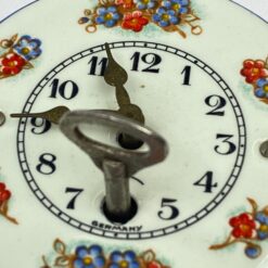 Mechaninis žalvario ir emaliuoto metalo miniatiūrinis sieninis laikrodis 4,5×6,5×12 cm