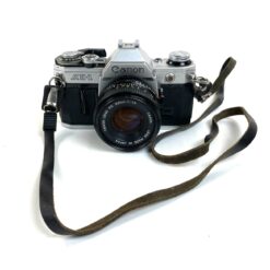 Vintažinis japoniškas Canon AE-1 juostinis fotoaparatas (neveikiantis) su Canon Lens FD 50 mm 1:18 objektyvu 8,5x14,5x9 cm