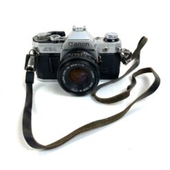 Vintažinis japoniškas Canon AE-1 juostinis fotoaparatas (neveikiantis) su Canon Lens FD 50 mm 1:18 objektyvu 8,5×14,5×9 cm